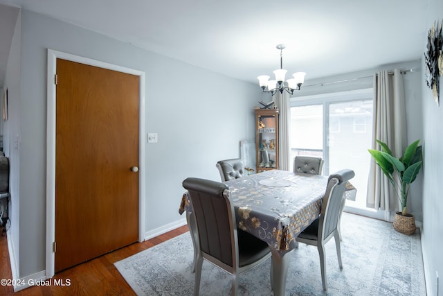 dining space with hardwood / wood-style floors and a notable chandelier