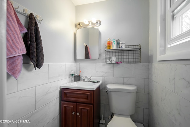 bathroom with vanity, tile walls, and toilet