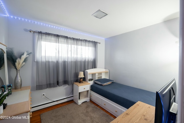 bedroom with baseboard heating and dark wood-type flooring