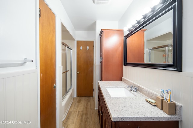 bathroom with vanity, wood-type flooring, and combined bath / shower with glass door