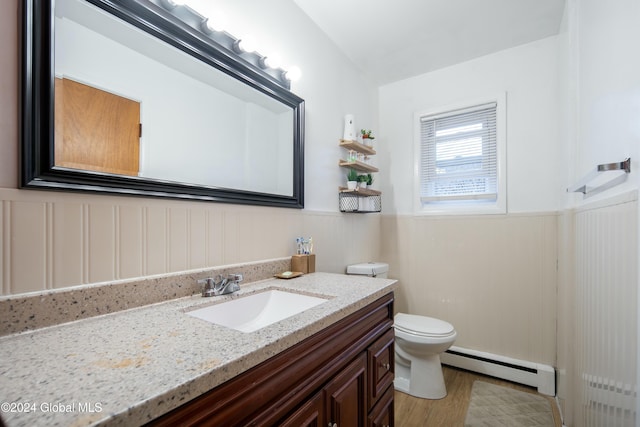 bathroom with hardwood / wood-style floors, vanity, toilet, and a baseboard heating unit