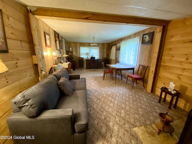 carpeted living room featuring wood walls and beamed ceiling