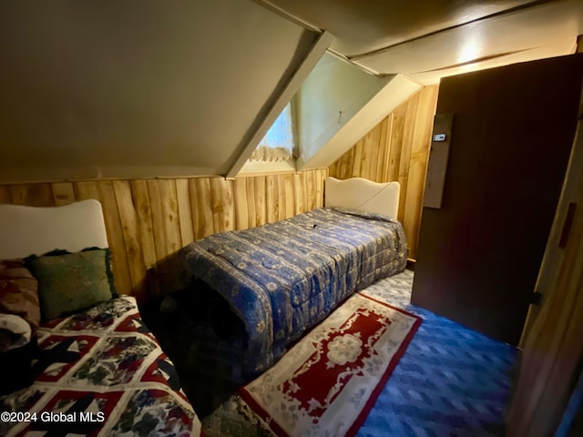 carpeted bedroom featuring vaulted ceiling and wood walls