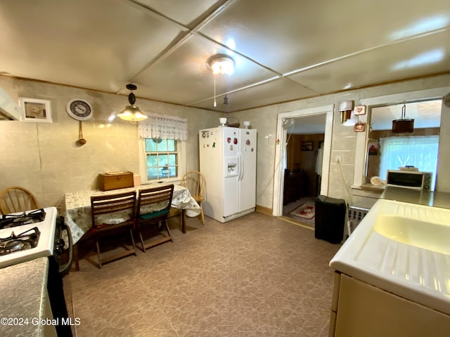 kitchen with gas range oven and white refrigerator with ice dispenser