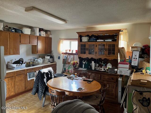 kitchen featuring stainless steel fridge, light parquet flooring, and a textured ceiling