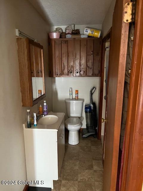 bathroom with a textured ceiling, vanity, and toilet