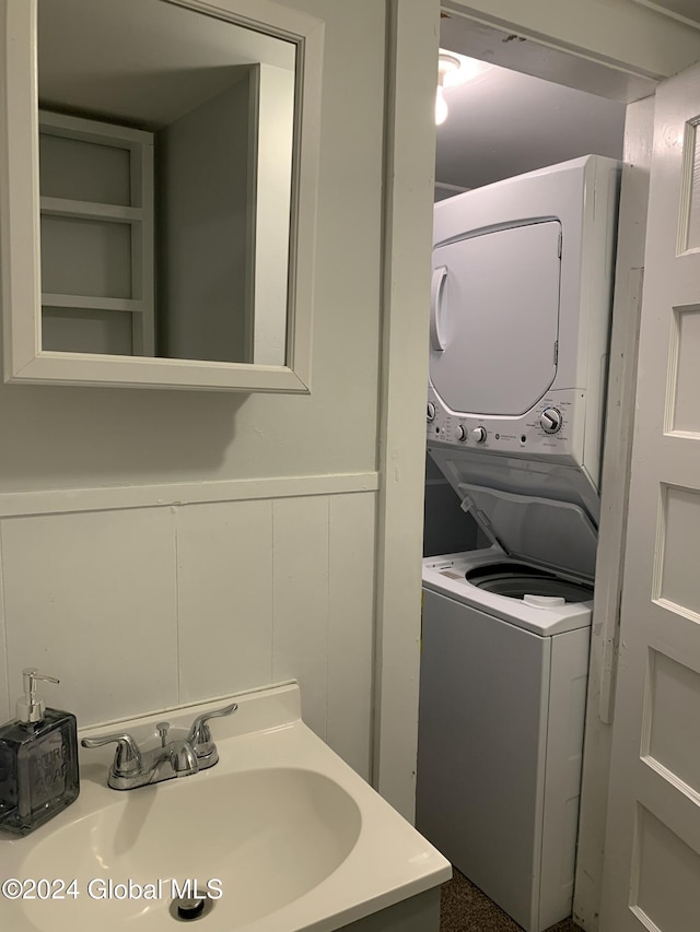 laundry area featuring stacked washing maching and dryer and sink