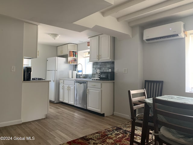 kitchen featuring a wall mounted air conditioner, white refrigerator, dishwasher, decorative backsplash, and white cabinets