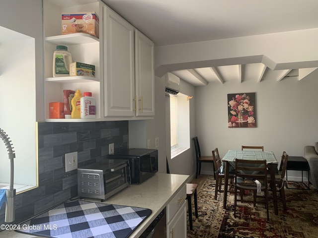 kitchen with backsplash, beamed ceiling, a wall unit AC, and white cabinets