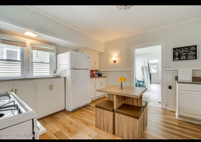 kitchen featuring white appliances, light hardwood / wood-style floors, and white cabinets