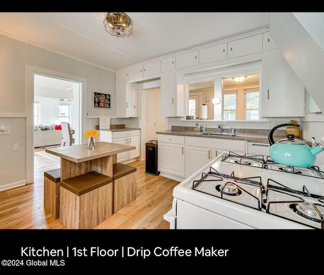 kitchen featuring white range with gas cooktop, sink, white cabinets, and light wood-type flooring