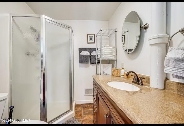 bathroom with a shower with door, vanity, and tile patterned floors