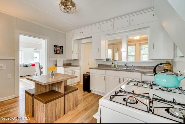 kitchen with white cabinetry, sink, white gas stove, and light hardwood / wood-style flooring