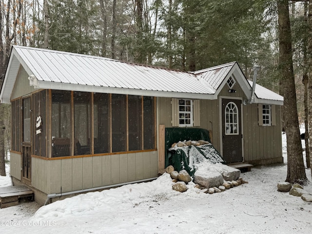 snow covered structure with a sunroom