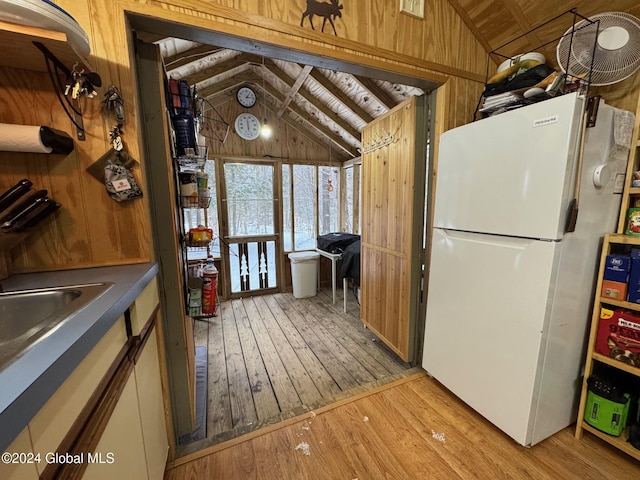 kitchen with light hardwood / wood-style floors, wood ceiling, white fridge, lofted ceiling, and wood walls