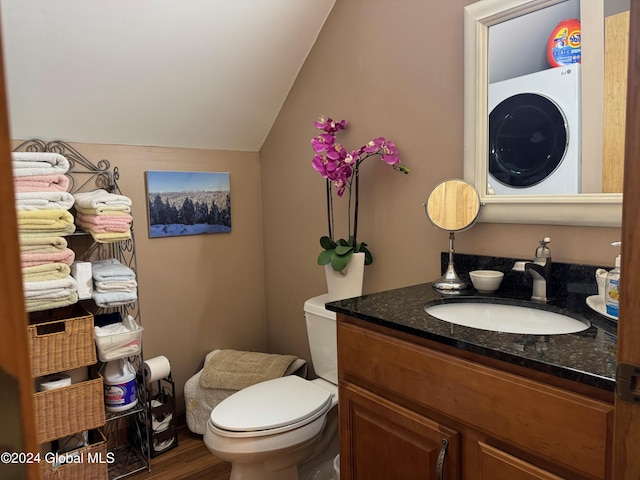 bathroom with washer / dryer, hardwood / wood-style floors, vaulted ceiling, toilet, and vanity