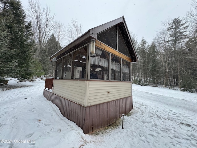 view of snowy exterior with a sunroom