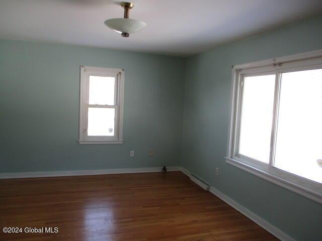 spare room with dark hardwood / wood-style floors and a healthy amount of sunlight