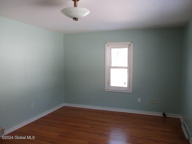 unfurnished room with a baseboard radiator and dark hardwood / wood-style floors