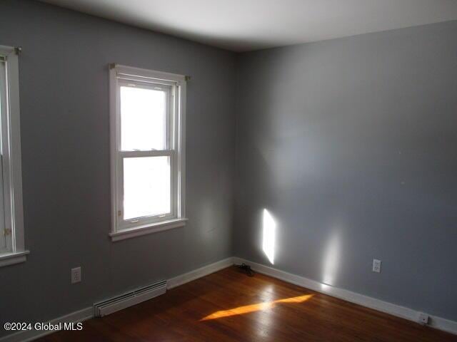 spare room with dark hardwood / wood-style flooring and a baseboard heating unit