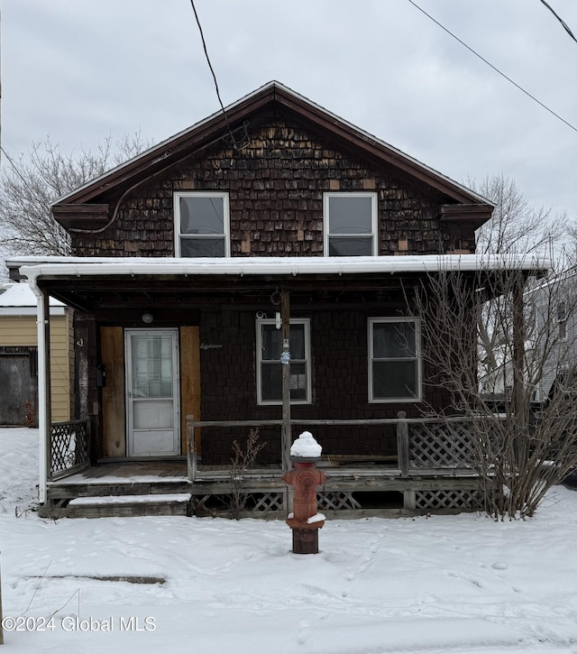 snow covered rear of property featuring covered porch