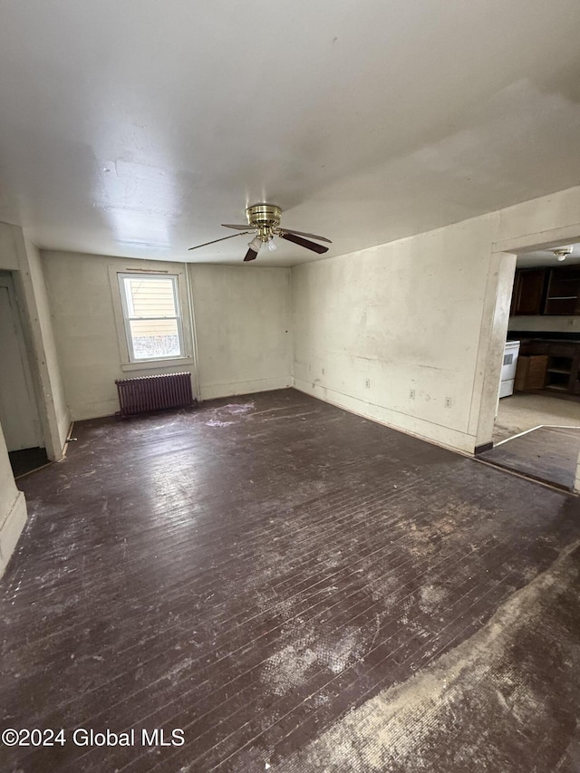 unfurnished living room featuring radiator heating unit, dark hardwood / wood-style floors, and ceiling fan