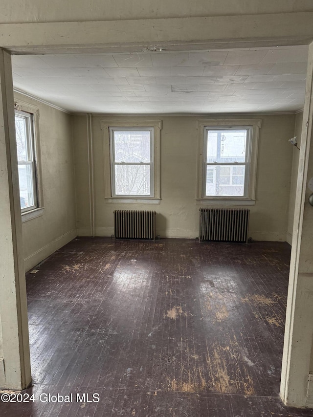 empty room featuring radiator heating unit and dark wood-type flooring