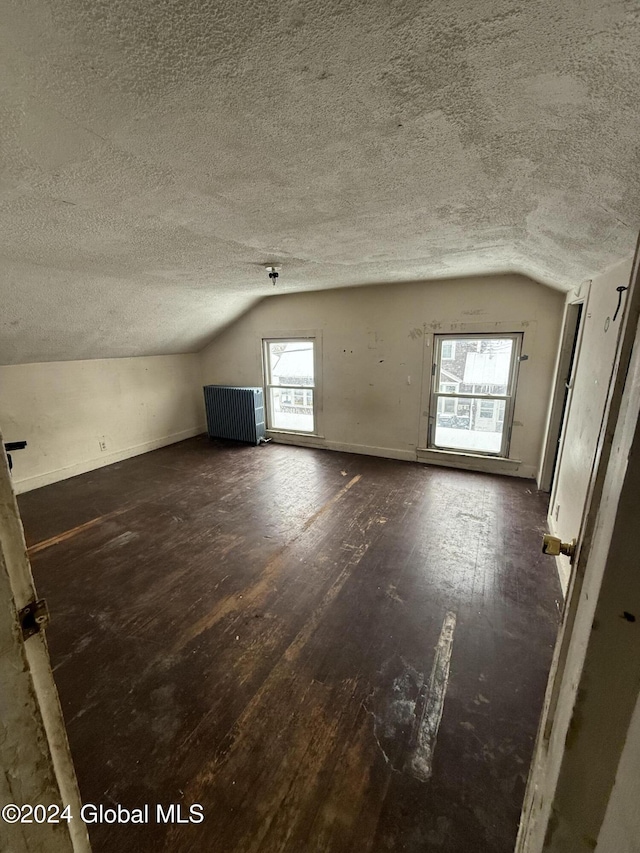 bonus room with a textured ceiling, dark hardwood / wood-style floors, and vaulted ceiling