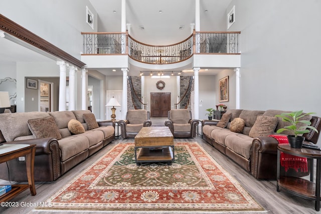 living room featuring ornate columns, a towering ceiling, and light hardwood / wood-style floors