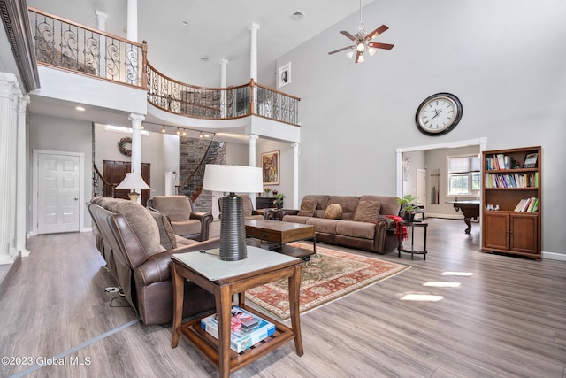 living room featuring ceiling fan, decorative columns, a towering ceiling, hardwood / wood-style flooring, and pool table