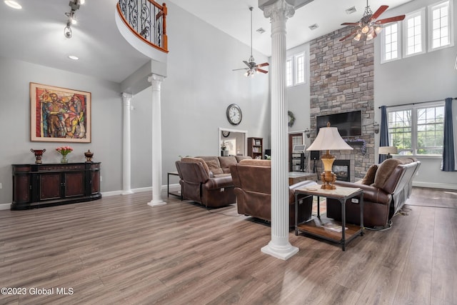 living room with hardwood / wood-style floors, ornate columns, a fireplace, and a towering ceiling