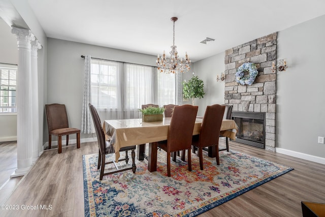 dining space featuring a notable chandelier, a fireplace, a wealth of natural light, and decorative columns