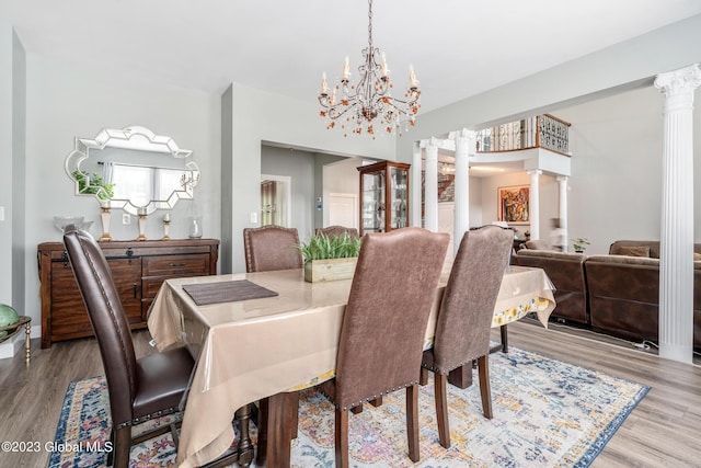 dining area featuring decorative columns, light hardwood / wood-style flooring, and a chandelier