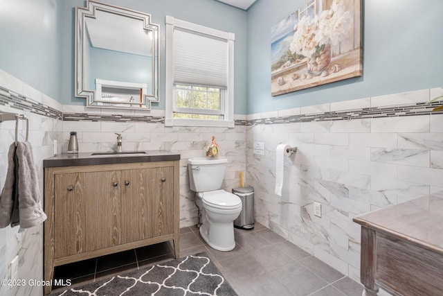 bathroom featuring tile patterned floors, vanity, toilet, and tile walls