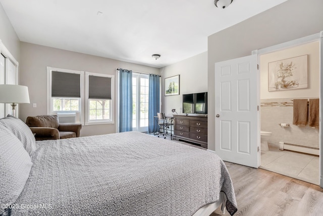 bedroom with ensuite bathroom, light hardwood / wood-style flooring, and a baseboard heating unit