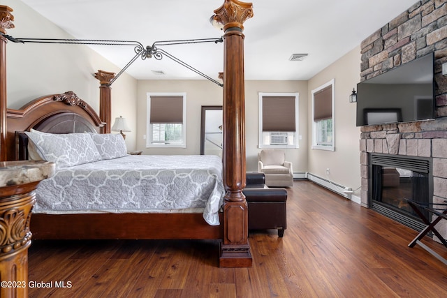 bedroom with a fireplace, dark hardwood / wood-style flooring, cooling unit, and a baseboard heating unit