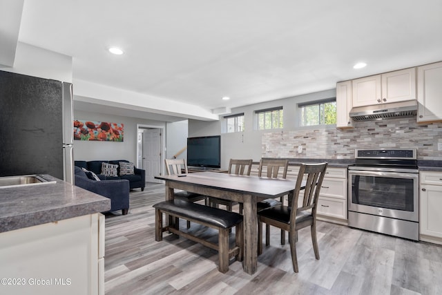 kitchen featuring tasteful backsplash, white cabinetry, light wood-type flooring, and appliances with stainless steel finishes