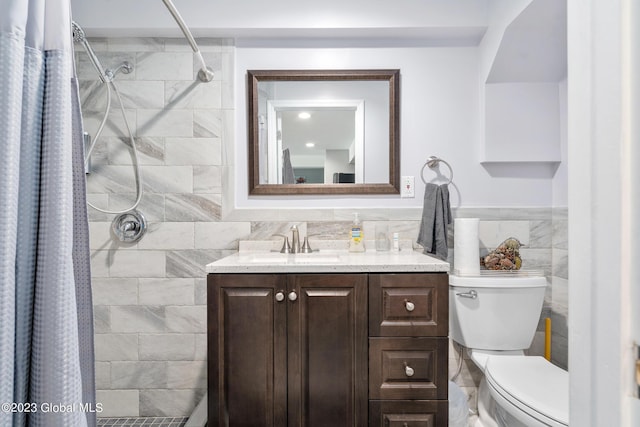 bathroom with toilet, vanity, tile walls, and walk in shower