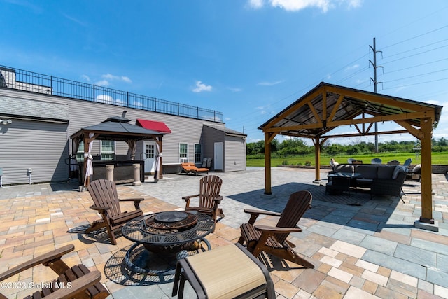 view of patio / terrace featuring a gazebo, a storage shed, and an outdoor living space with a fire pit