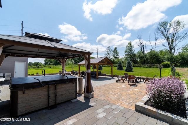 view of patio / terrace featuring a gazebo, a hot tub, and a fire pit