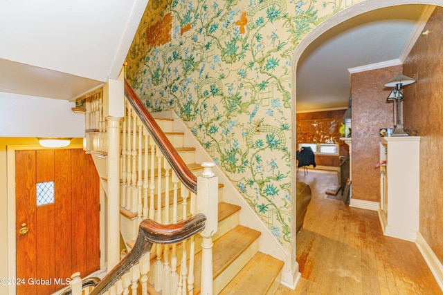 stairs with hardwood / wood-style floors and ornamental molding