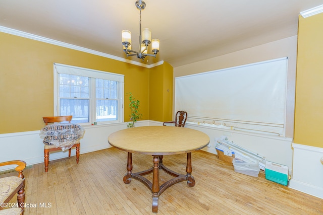 dining space with hardwood / wood-style floors, ornamental molding, and a notable chandelier