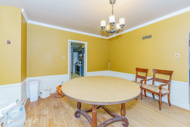 dining room with wood-type flooring, ornamental molding, and a chandelier