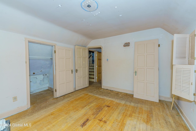 unfurnished bedroom featuring hardwood / wood-style floors and lofted ceiling