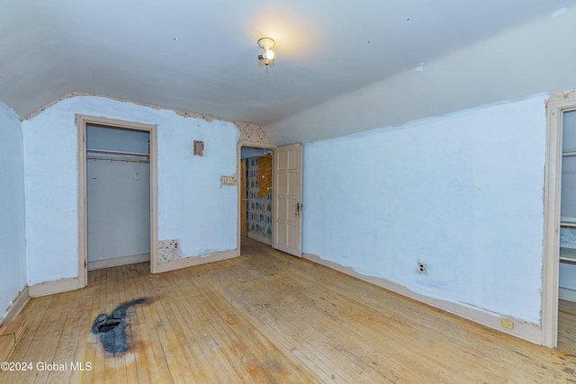 unfurnished bedroom with a closet, lofted ceiling, and light hardwood / wood-style flooring