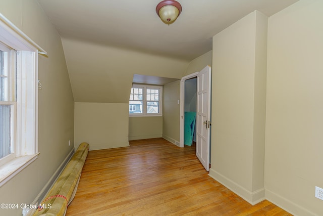 additional living space with a baseboard heating unit, light hardwood / wood-style flooring, and vaulted ceiling