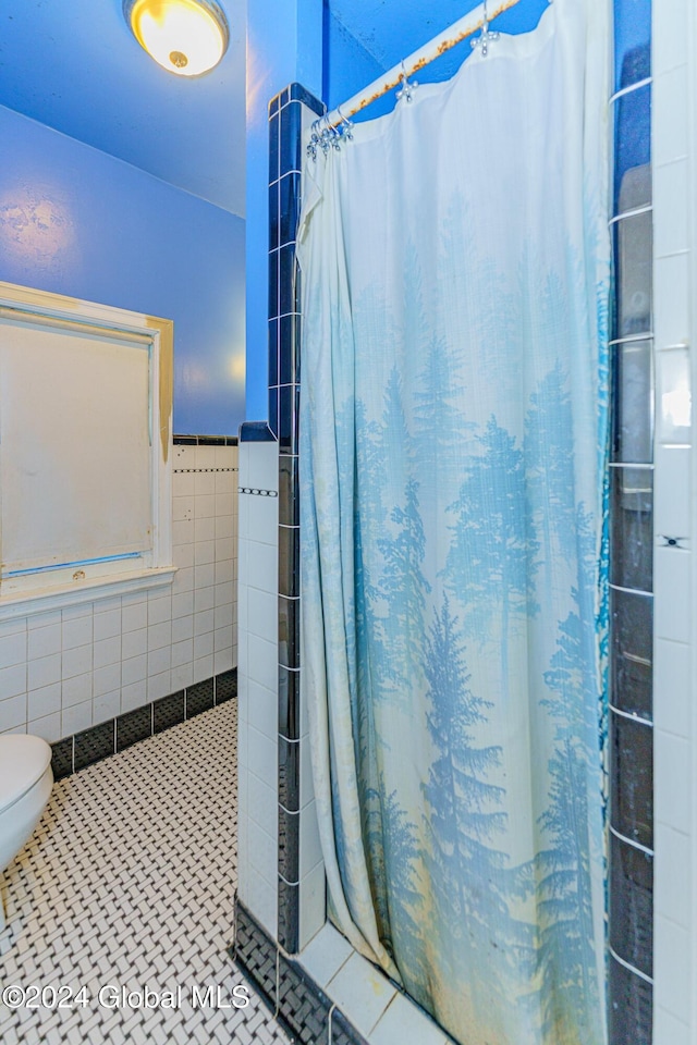 bathroom featuring tile patterned flooring, curtained shower, toilet, and tile walls