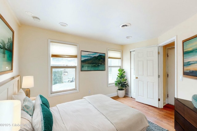 bedroom with light wood-style floors, baseboards, and visible vents