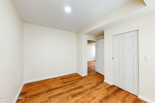 unfurnished bedroom featuring a closet, light wood-style floors, and baseboards