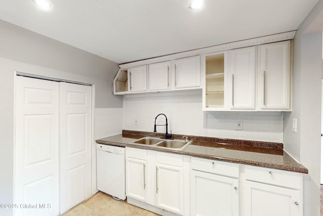 kitchen with light tile patterned floors, white cabinets, dishwasher, a sink, and decorative backsplash